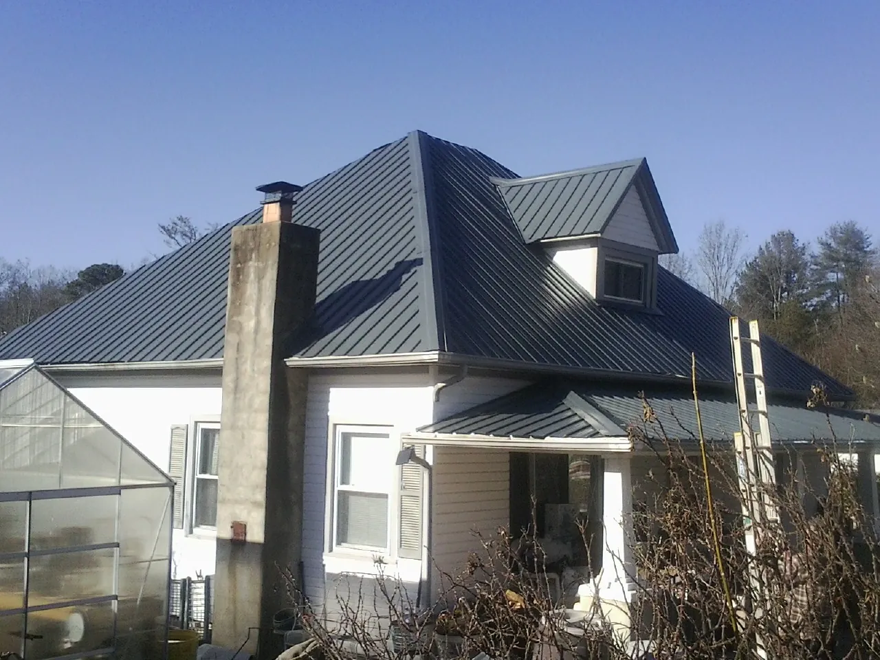 Dark blue standing seam metal roof on a white farmhouse with dormer — Slate & Tile Roof Repair by Roofing Brothers in Olney