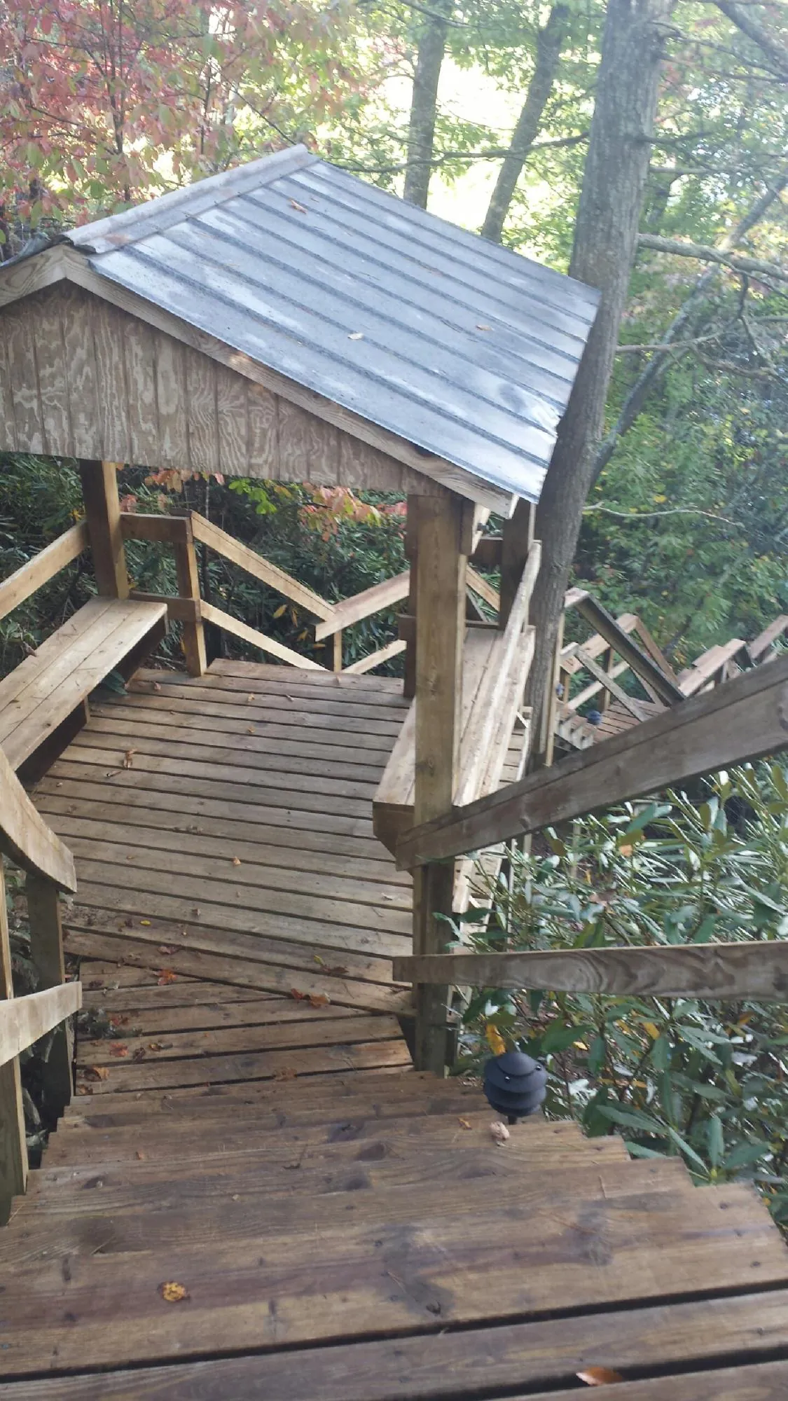 Metal roofed shelter over wooden steps on a wooded walkway — Skylight Repair & Installation work by our crew in Olney