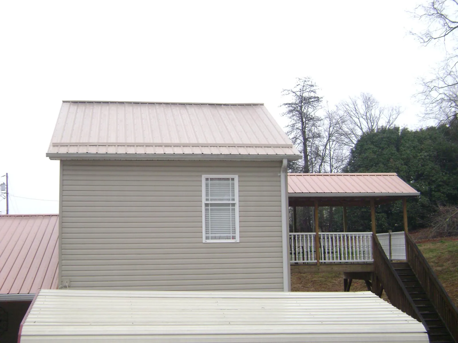 Tan metal roofs on a two story addition and attached porch, from a Roof Replacement job in Olney